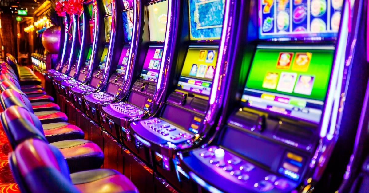 Row of colorful slot machines glows with purple, blue, and green lights inside a modern casino.